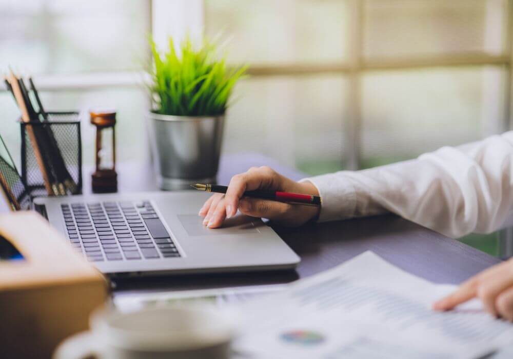Image of hand using laptop with documents, representing article discussing how recruiters can compare insurance quotes properly