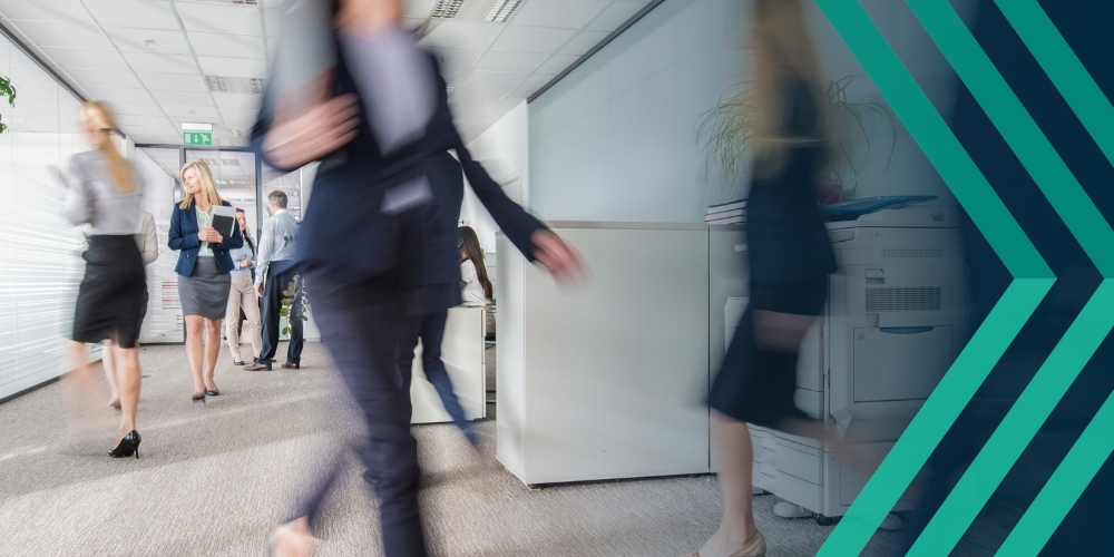Blurred figures walking through a busy office environment, representing article on recruiter risks and how insurance can help