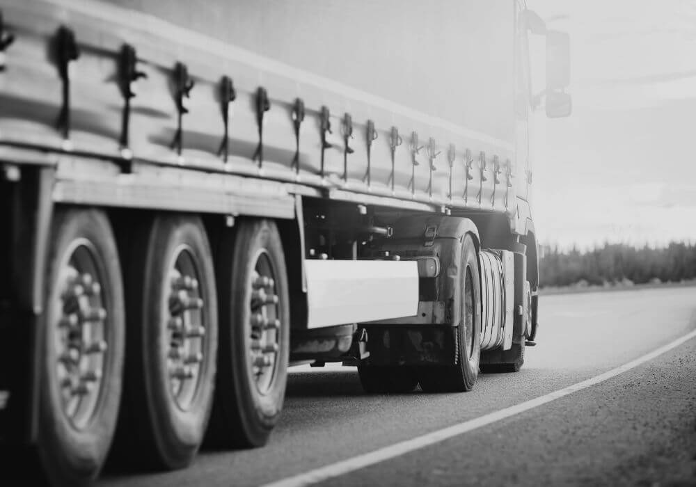 Black and white close-up image of heavy goods vehicle, representing article looking at temporary driver shortages and recruiter risks from rushed hiring